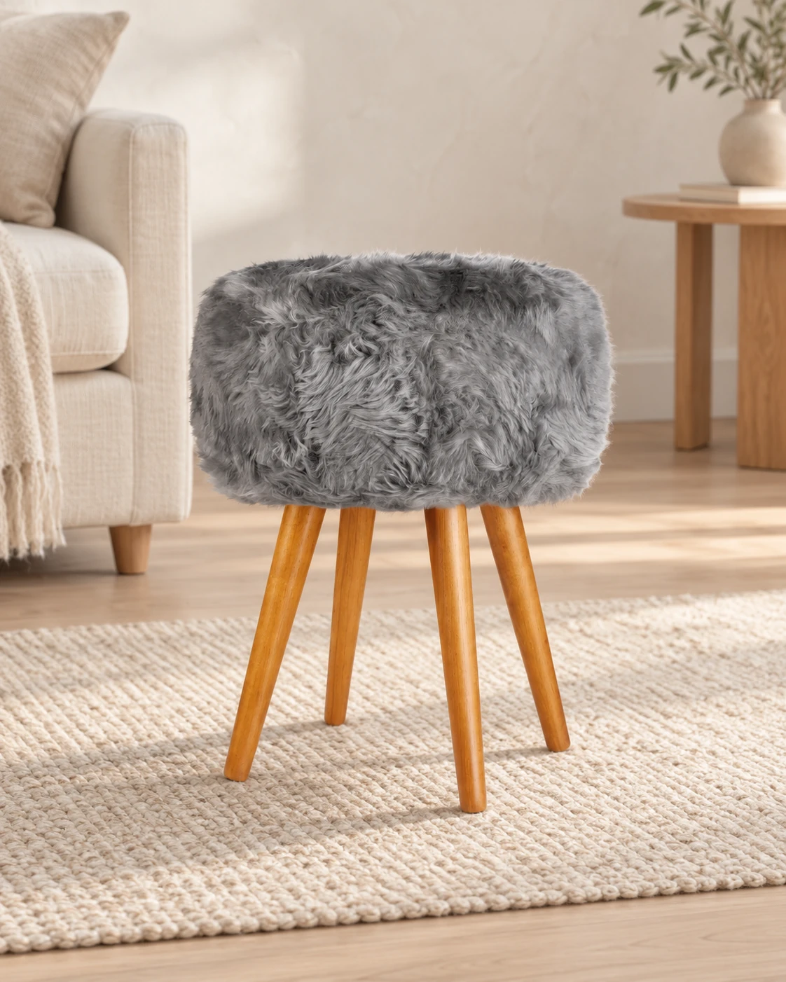 Grey sheepskin stool with oak legs in a light living room with cream upholstered furniture