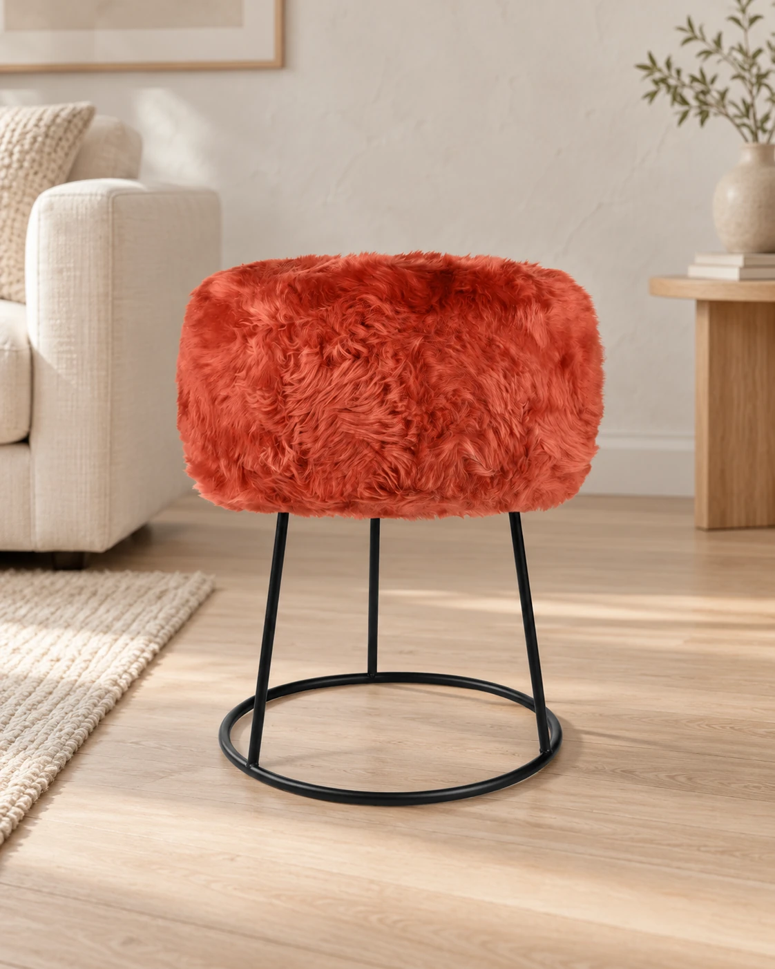 Burnt Orange sheepskin stool with a black circular metal base in a light living room with cream upholstered furniture