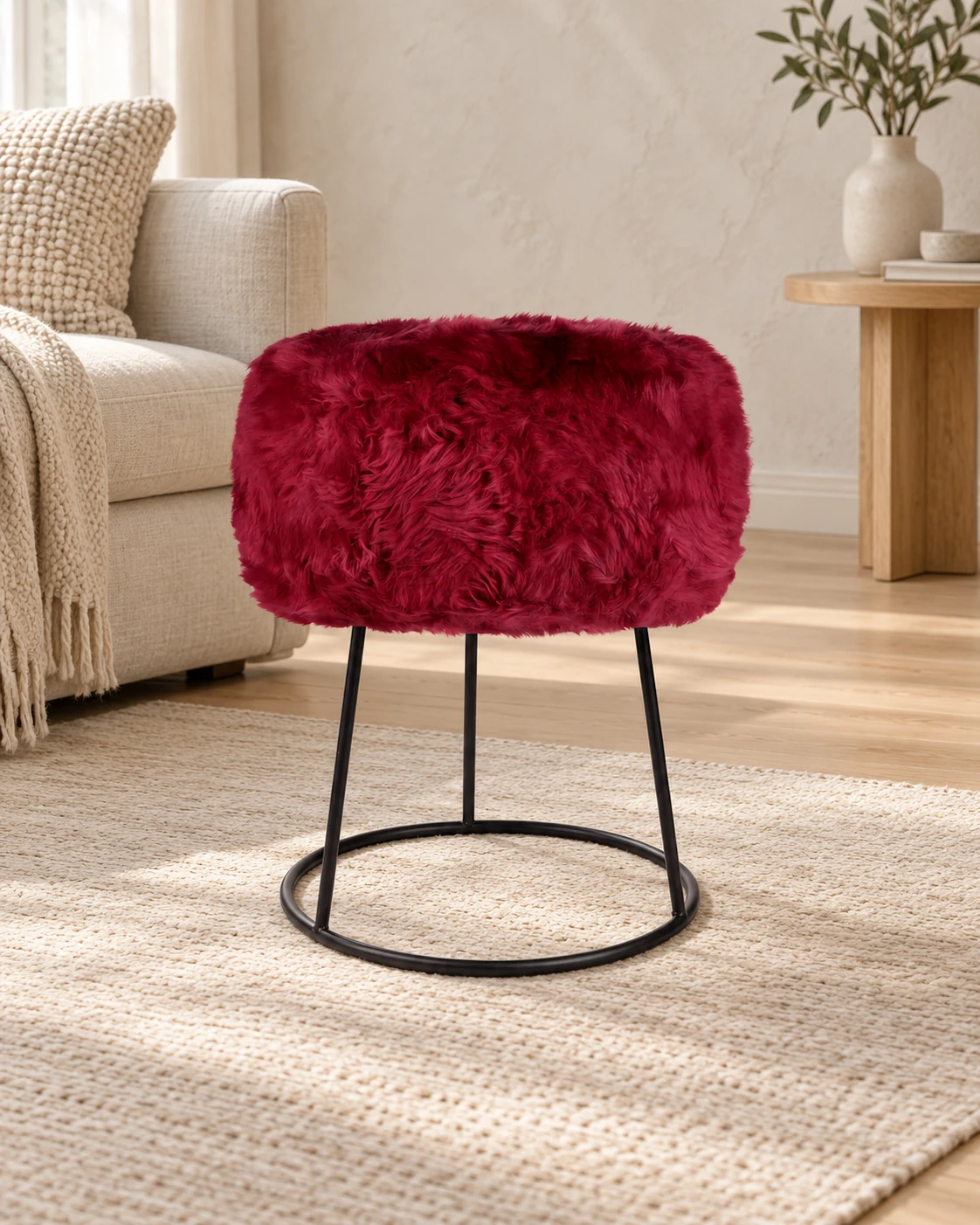 Fuchsia Pink sheepskin stool with a black circular metal base in a light living room with cream upholstered furniture