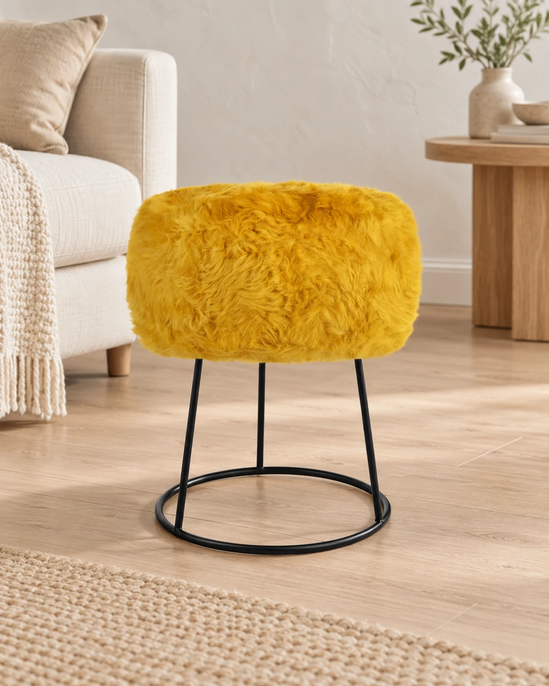 Warm Ochre sheepskin stool with a black circular metal base in a light living room with cream upholstered furniture